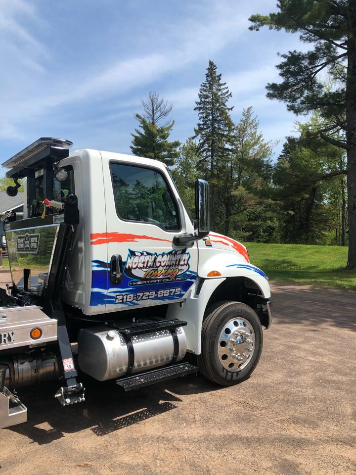 Tow truck with evergreen trees in the background